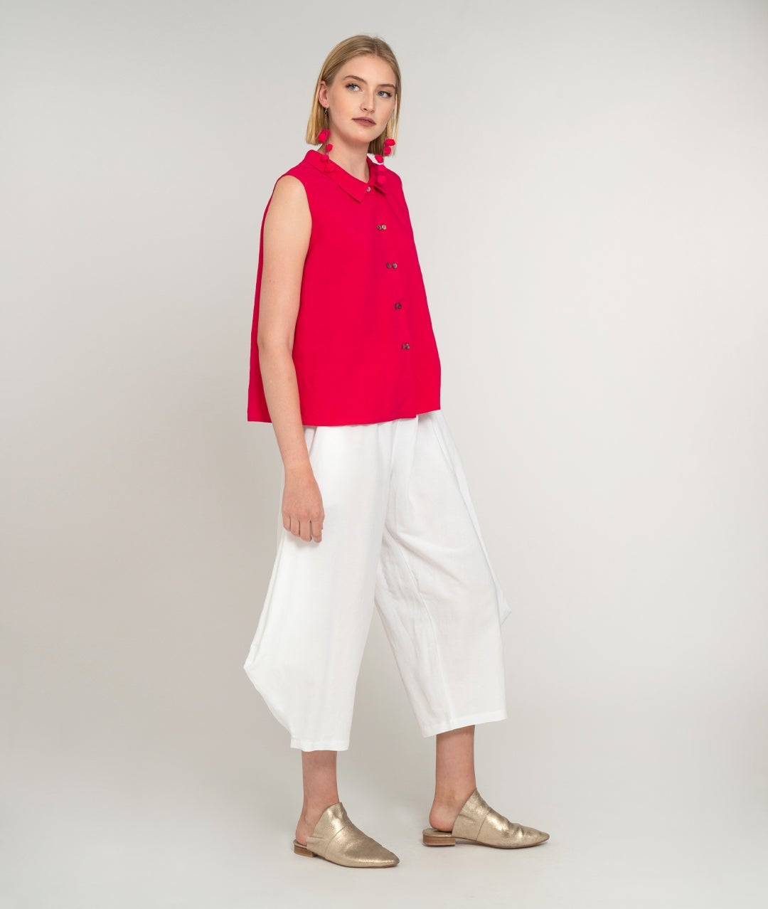 model in a wide leg white pant with a raspberry pink sleeveless button up blouse