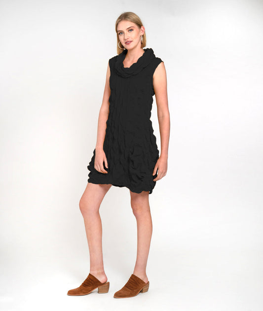 model in a black sleeveless tunic with a soft cowl neck, pockets and a beautiful pleating details along the lower portion of the princess seams at the hips.