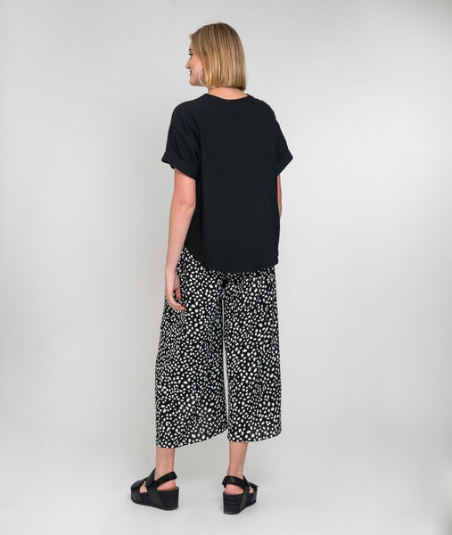 model in a wide leg black and white dot print pant with a faux wrap front, worn with a solid black boxy top