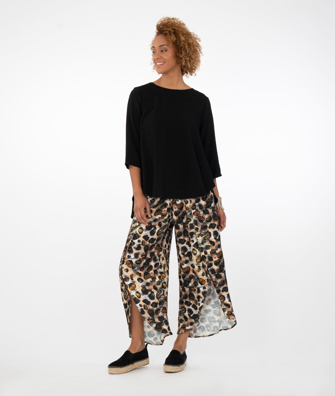 model in a solid black top with animal print pants in front of a white background