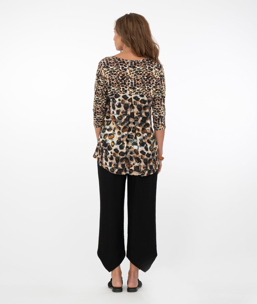 brunette model in a safari print top with black pants in front of a white background