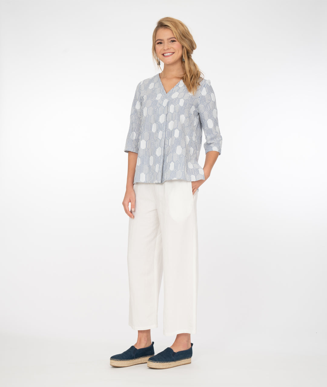 model in a wide leg white pant with a blue and white stripe and dot print top