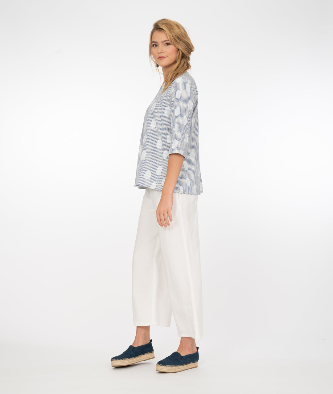 model in a wide leg white pant with a blue and white stripe and dot print top