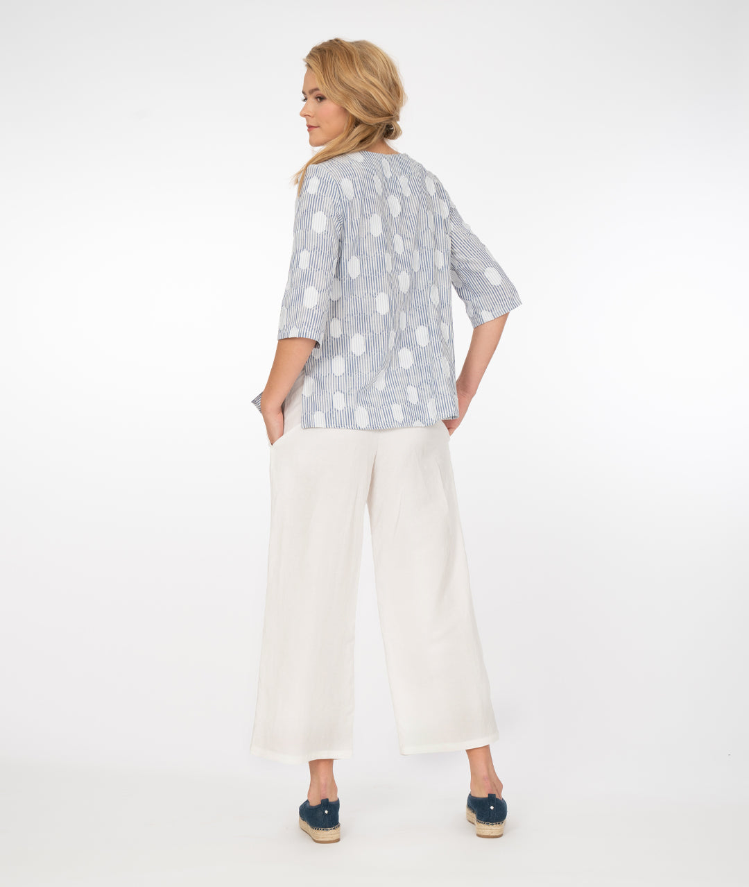 model in a wide leg white pant with a blue and white stripe and dot print top