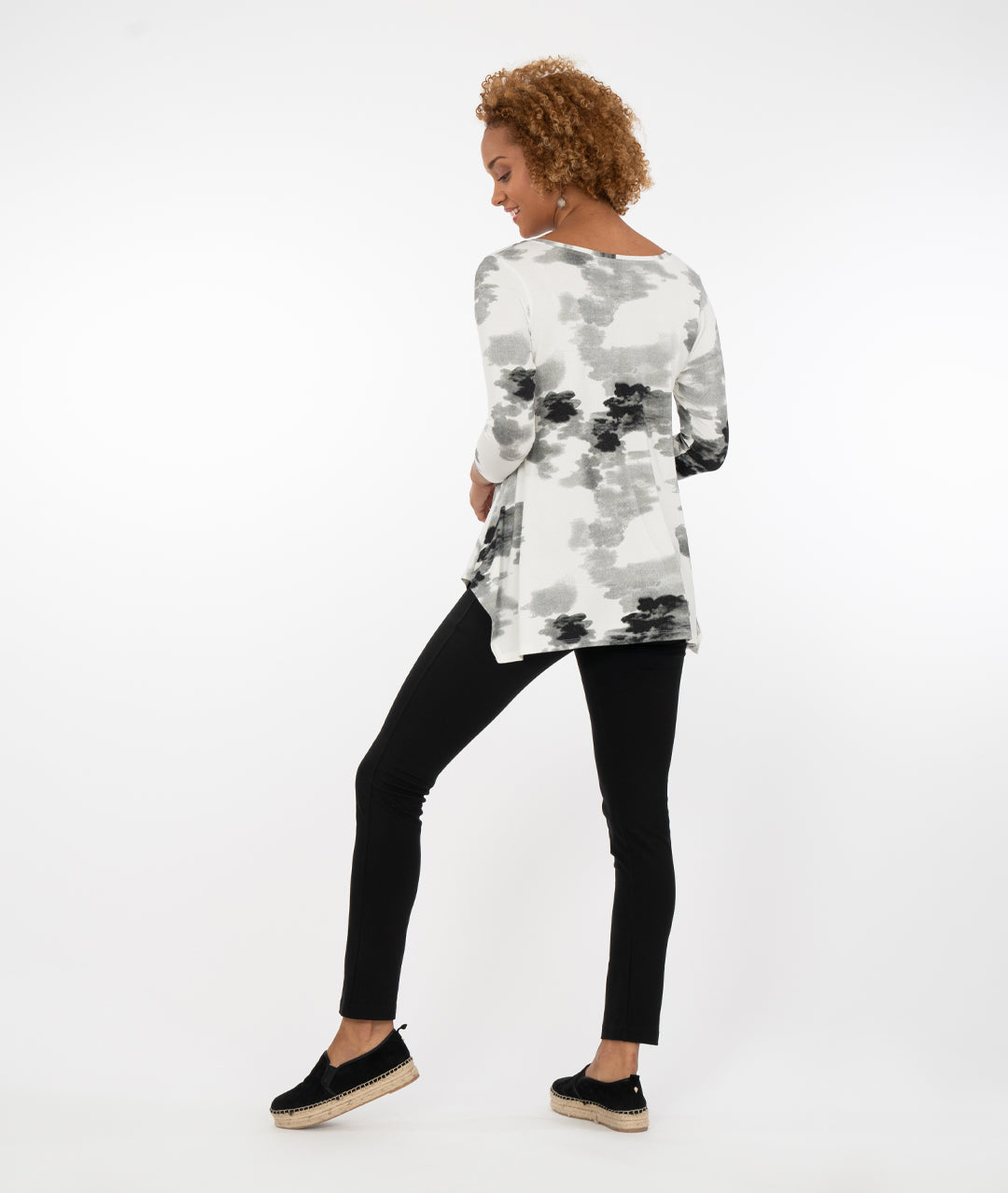 model wearing a black and white floral  top with black leggings in front of a white background