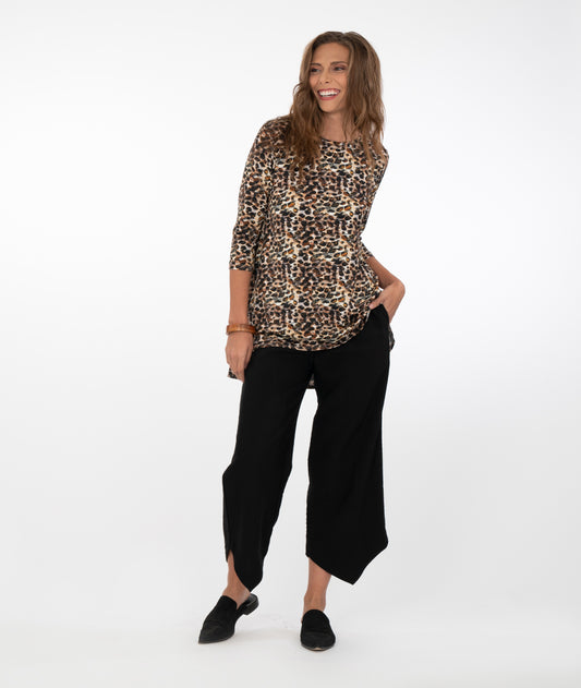brunette model in a safari print top with black pants in front of a white background