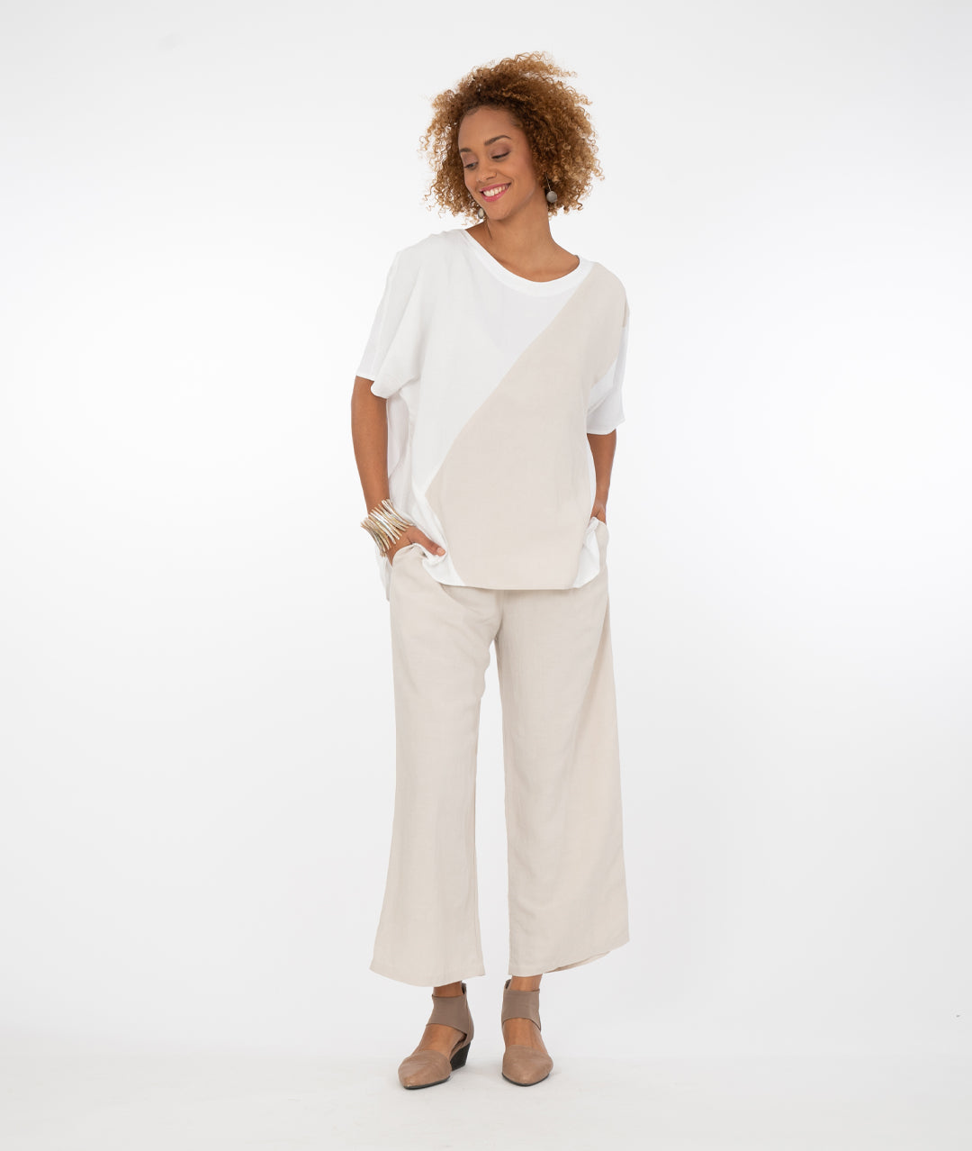 model in a white pullover tshirt style top with a contrasting color block across the body in a khaki color, with wide leg khaki color pants