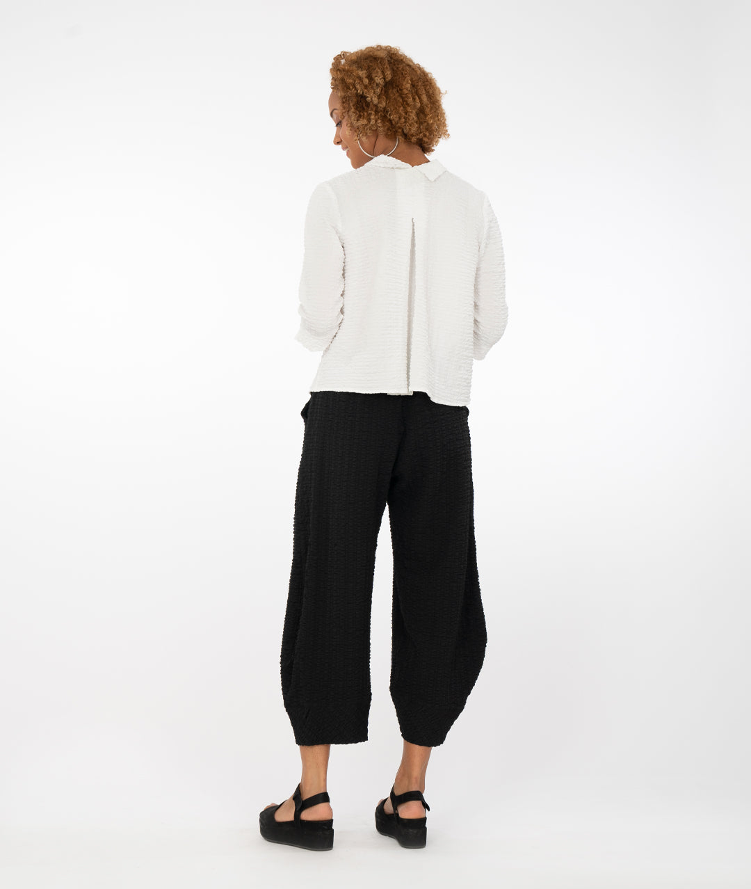 model with a white button up shirt with a black pant in front of a white back ground