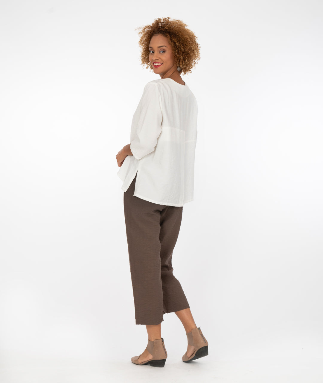 model in a white vneck top with a cropped brown pant