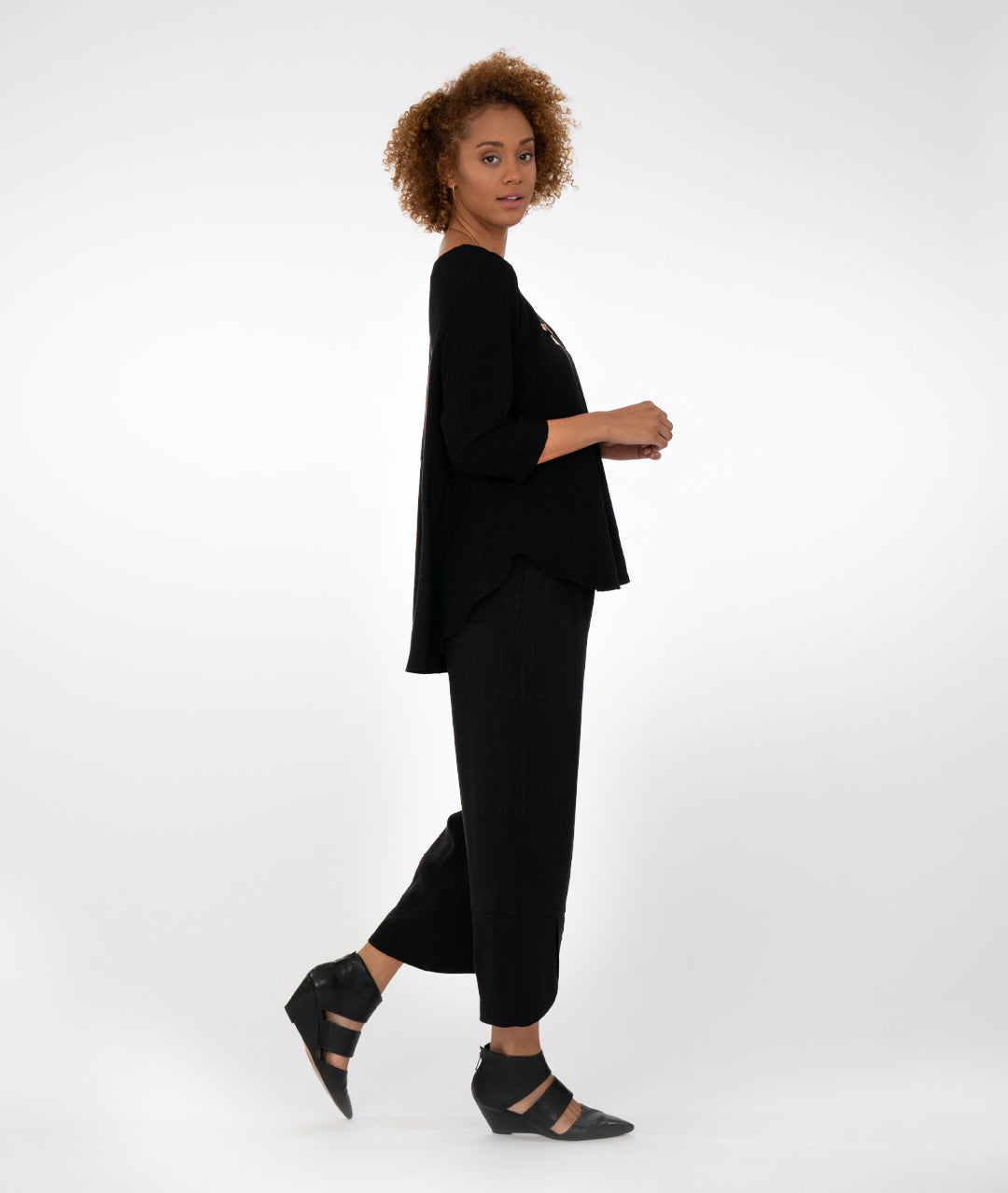 model in a black pant with a matching black top with a lower hem in the back