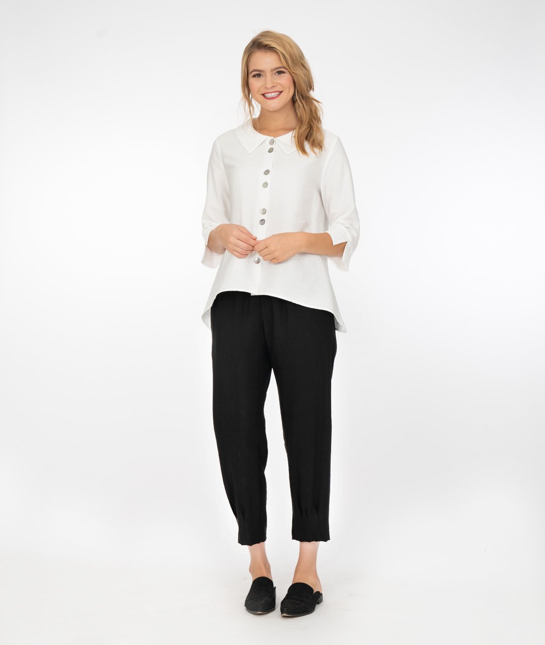 model in a white button up jacket with a collar and splits at the cuffs of the sleeves. Wearing black pants and shoes, standing in front of a white background