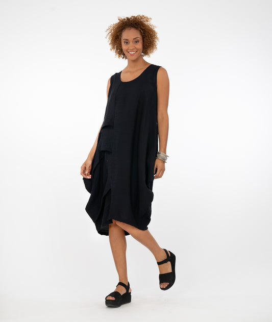 model in a sleeveless black dress with asymmetrical body and pleat detail