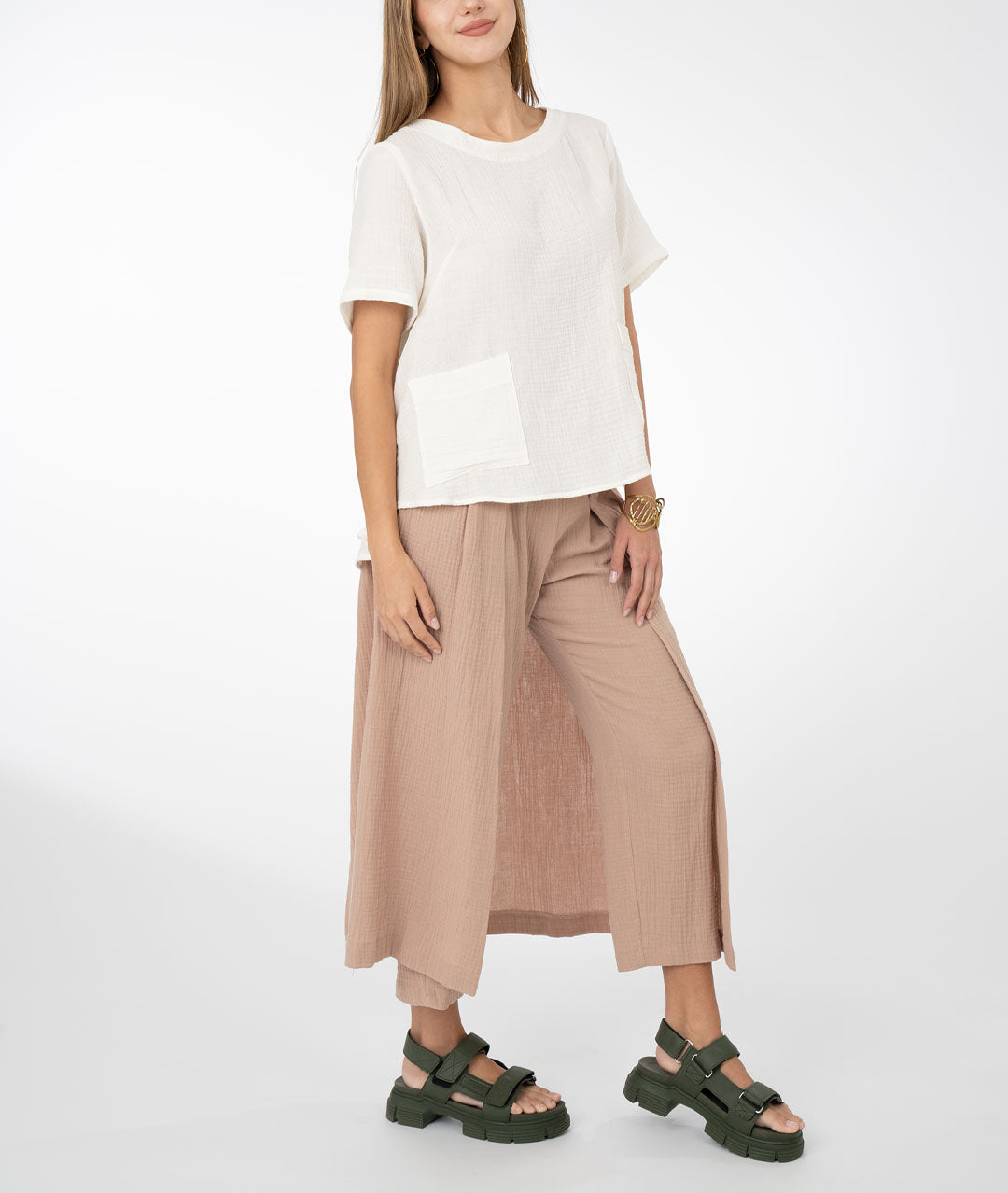 model in a khaki color pant with draped panels on either side, worn with a white boxy top with bust darts, square hip pockets and a slightly lower back