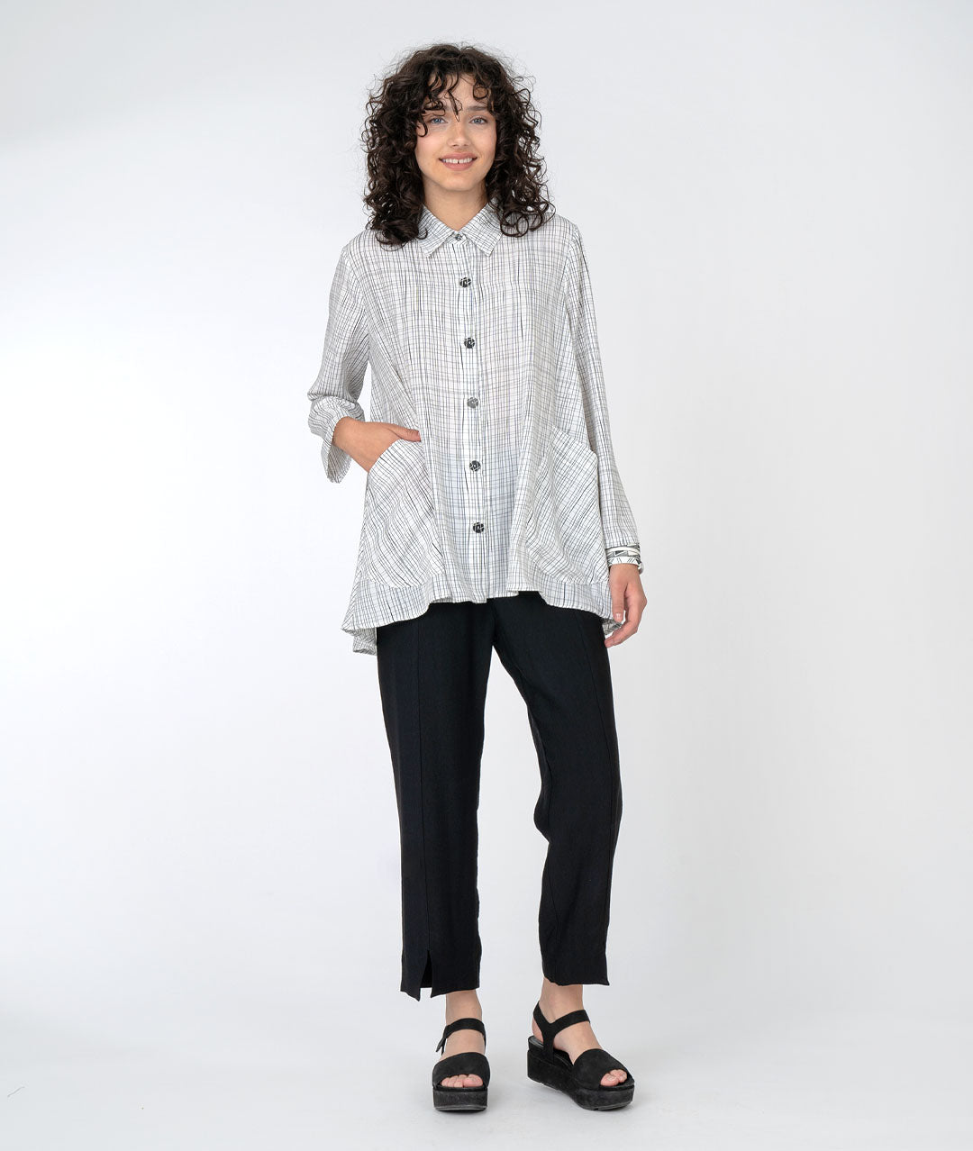 model in a slim black pant with a white button down top with a black grid print