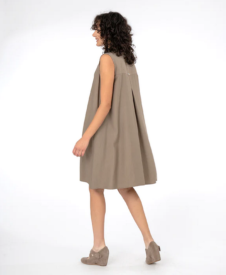 Side view of Brunette model wearing sleeveless shirt dress in in taupe and beige heels. On a white background.