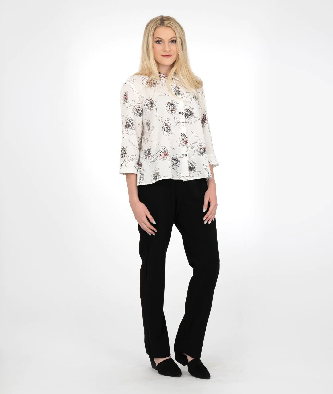 model in a white buttoned blouse with a red and black rose print, worn with black pants 