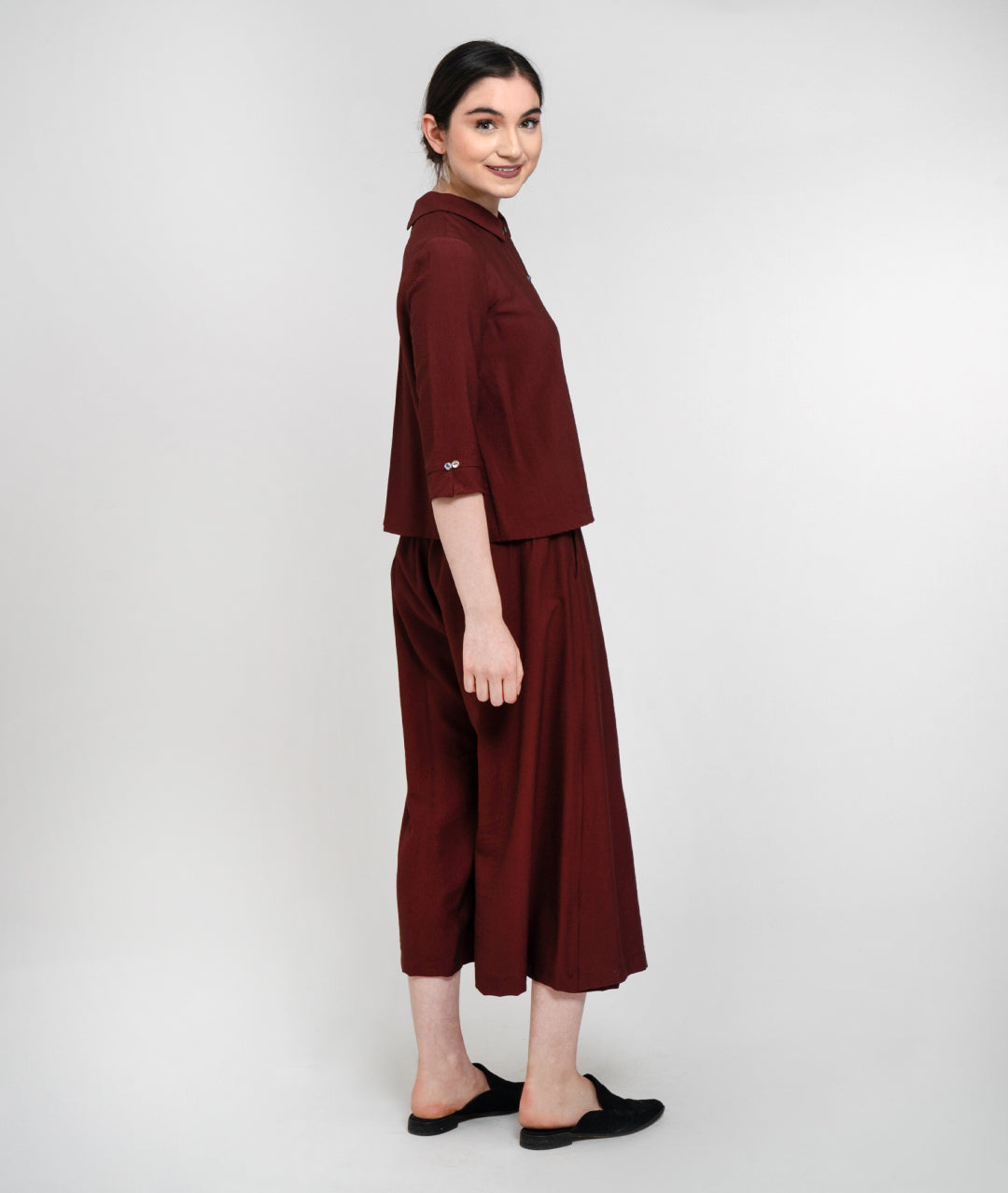 side view of model in a maroon button up top with a wide leg dark maroon pant