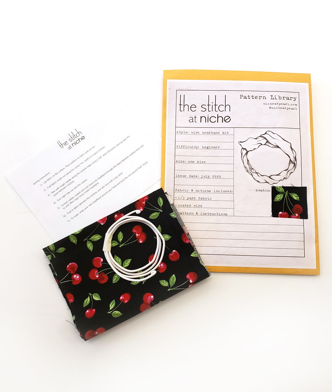 sewing pattern envelope with contents next to it, including a piece of fabric, wire and sewing instructions