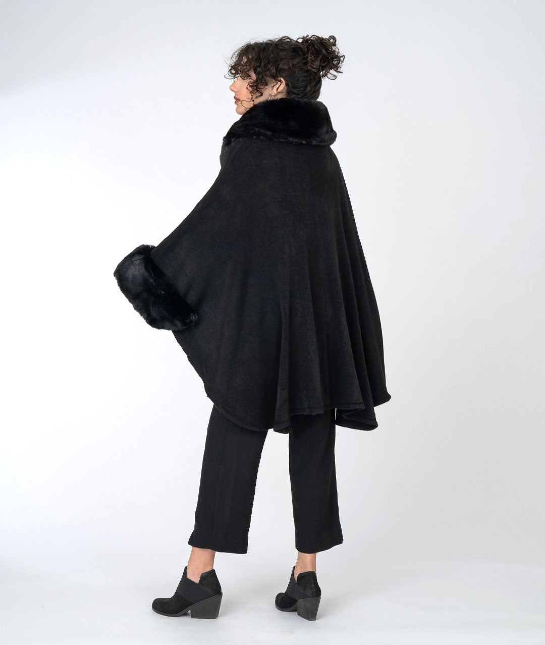 back view of black fur trimmed cape on model