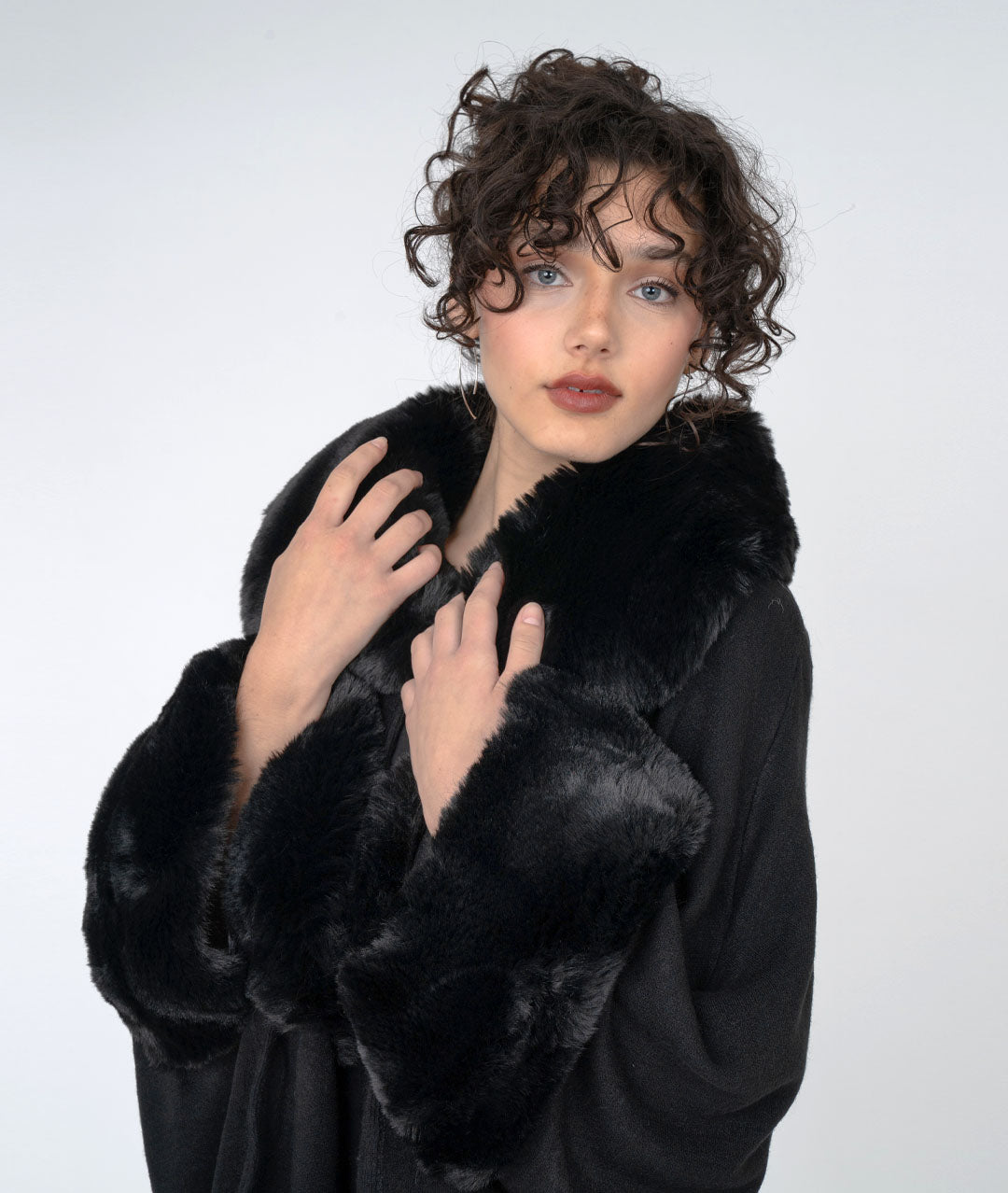 close-up of model wearing a black, fur trimmed cape