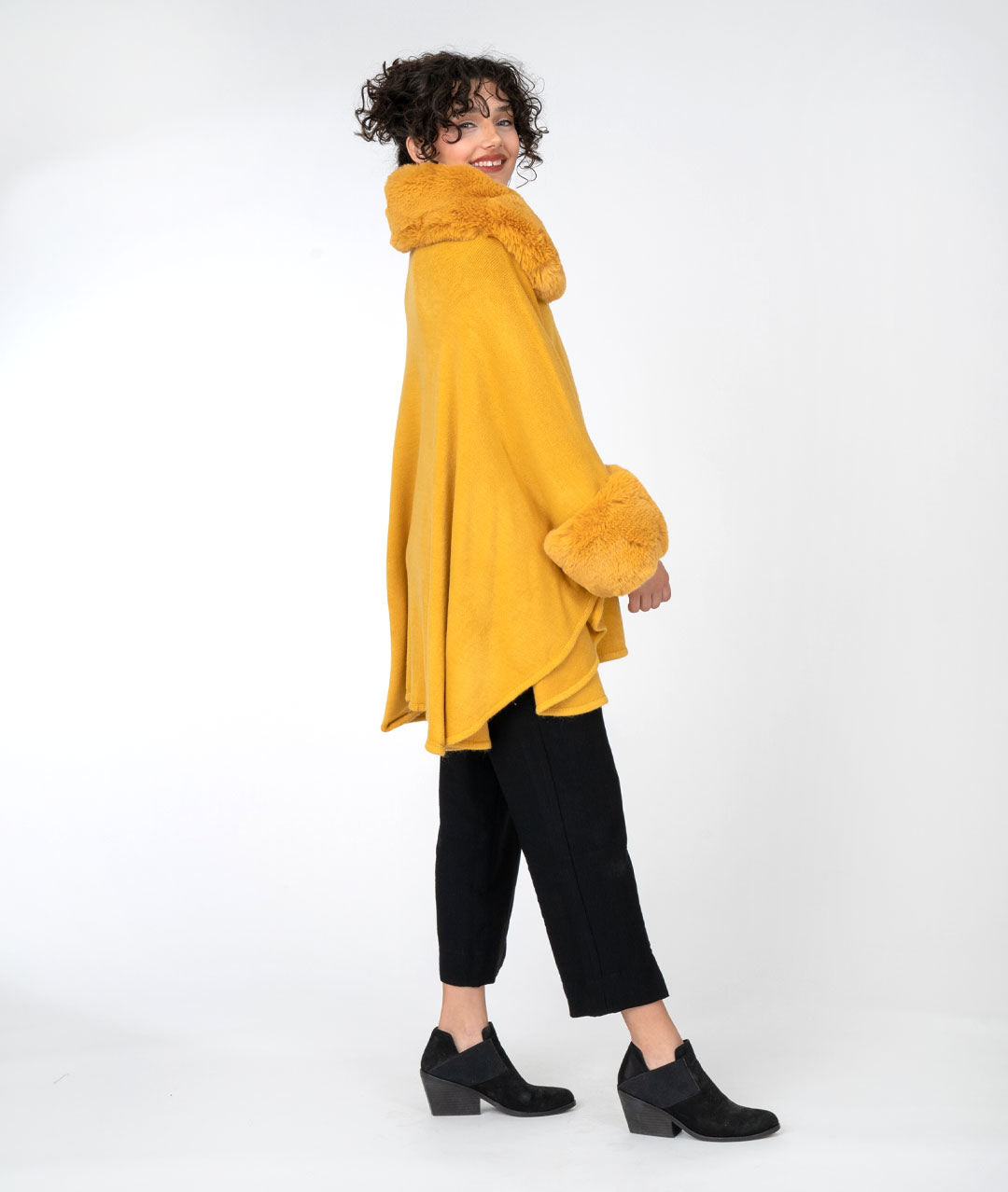 model is wearing all black with a mustard cape over top