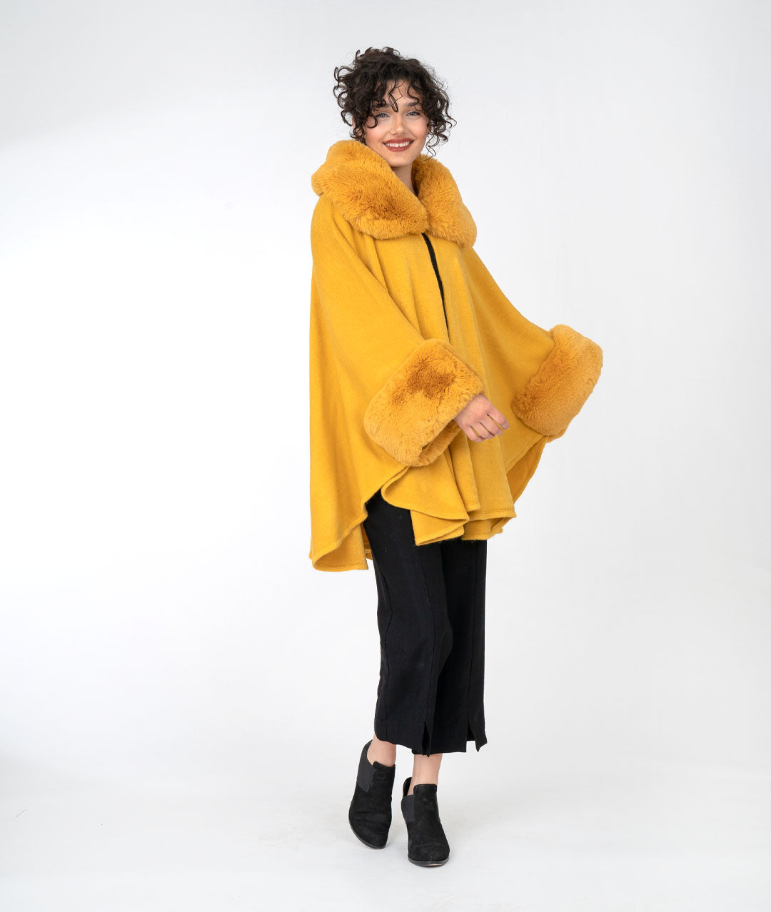 model is wearing all black with a mustard cape over top