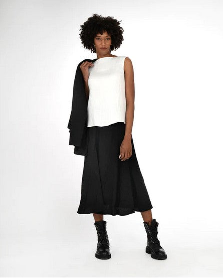 Model wearing a sleveless cream top,  black full skirt, and black combat boots. On a white background.