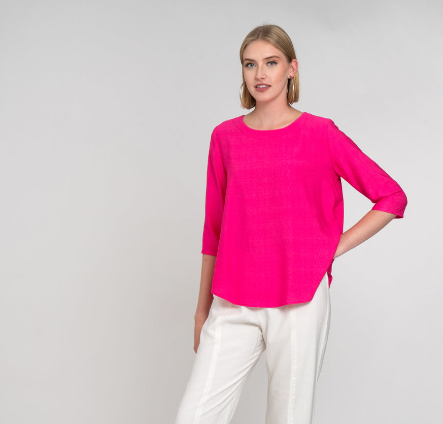 model in a hot pink top with a high-low hem, worn with a slim white pant